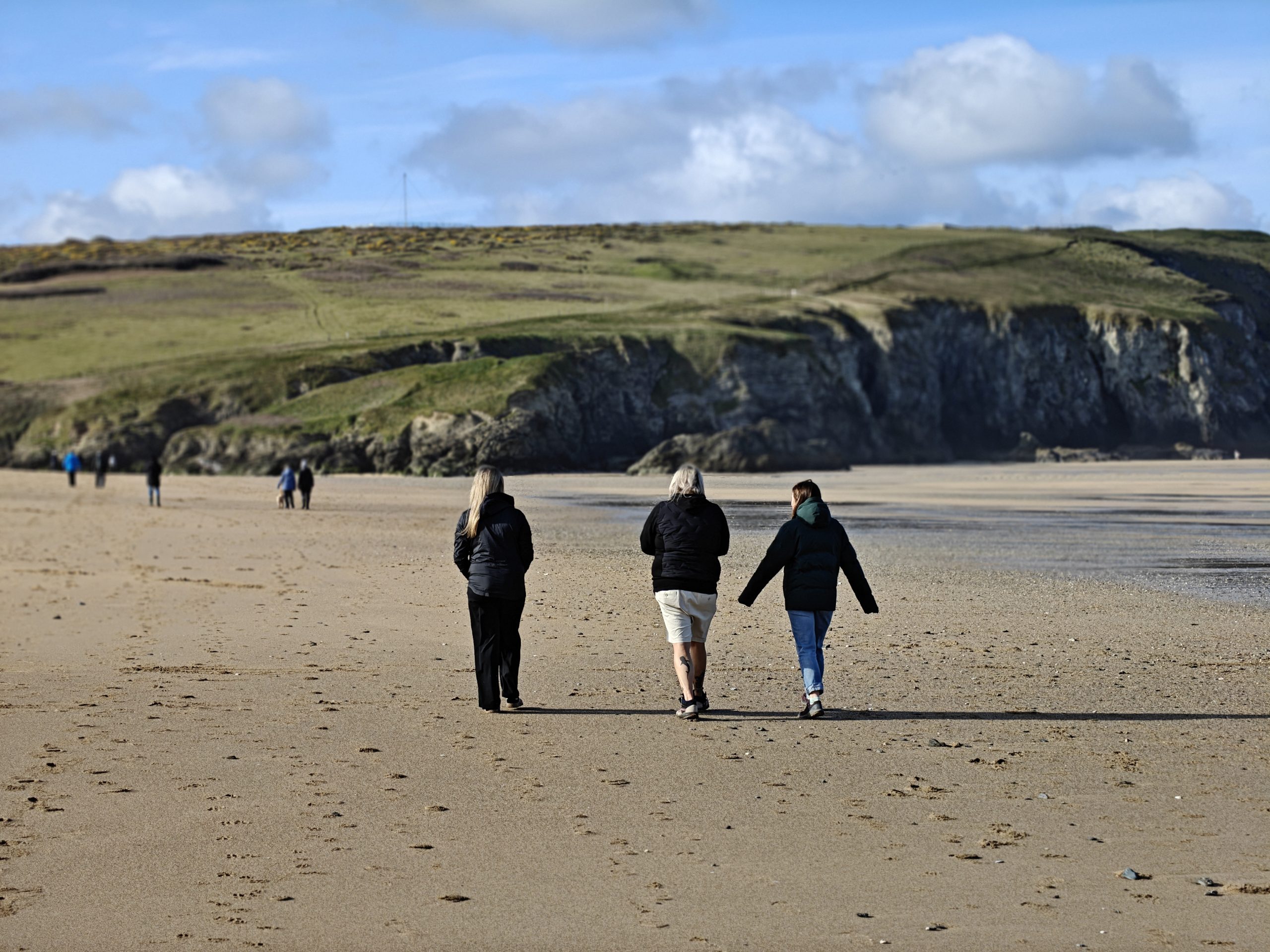 Three people walking and talking on the beach during a netwalk